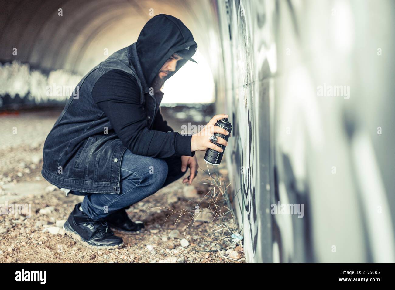 Vue latérale homme sweat à capuche peignant mur de graffiti Banque D'Images