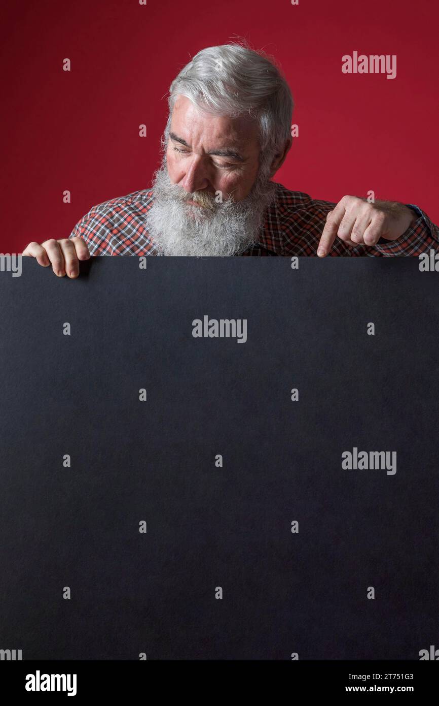 Gros plan homme âgé avec la barbe grise pointant son doigt blanc plaque noire Banque D'Images