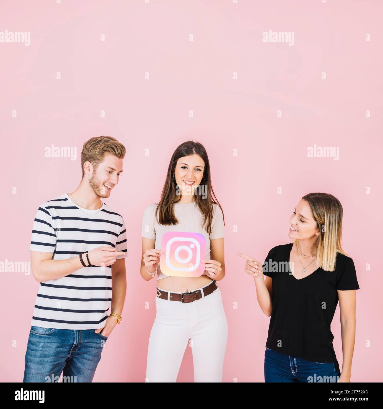 Femme homme heureux pointant leur ami tenant l'icône instagram Banque D'Images