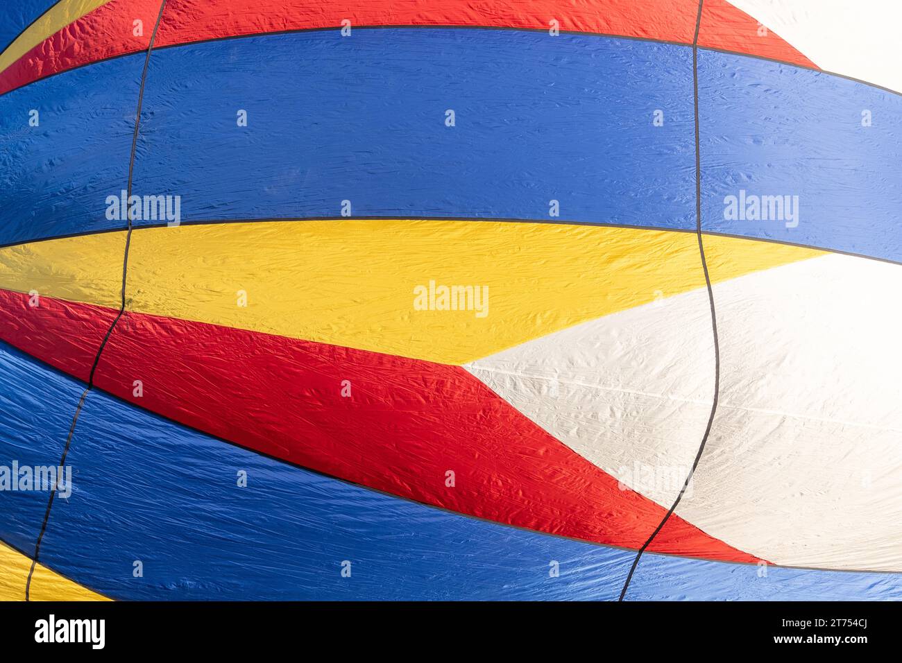 Détail abstrait de l'enveloppe multicolore d'une montgolfière gonflante avec des couleurs primaires et un motif géométrique en forme de flèche. Banque D'Images