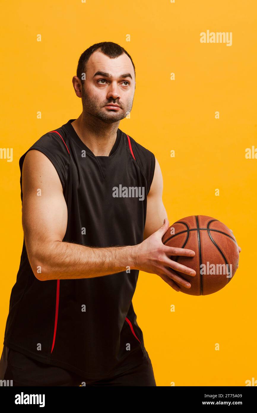 Joueur masculin de vue de face posant avec le basket-ball Banque D'Images