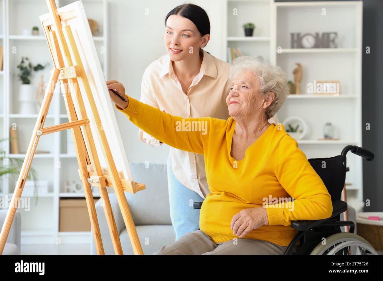 Femme aînée avec sa fille dessinant sur chevalet à la maison Banque D'Images