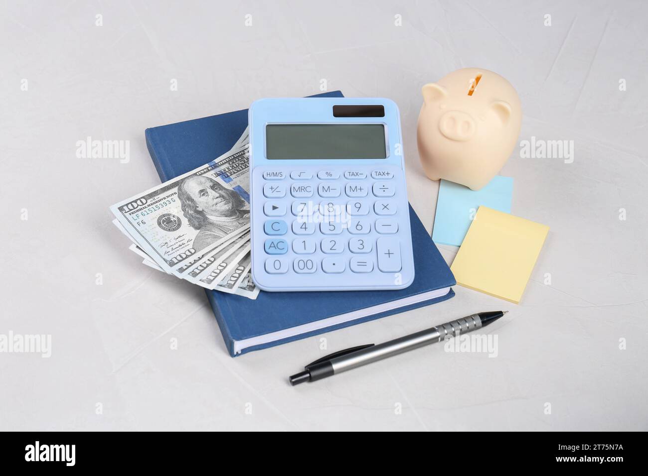 Calculatrice, billets de banque en dollars, tirelire, cahier, notes autocollantes et stylo sur la table gris clair. Concept de retraite Banque D'Images