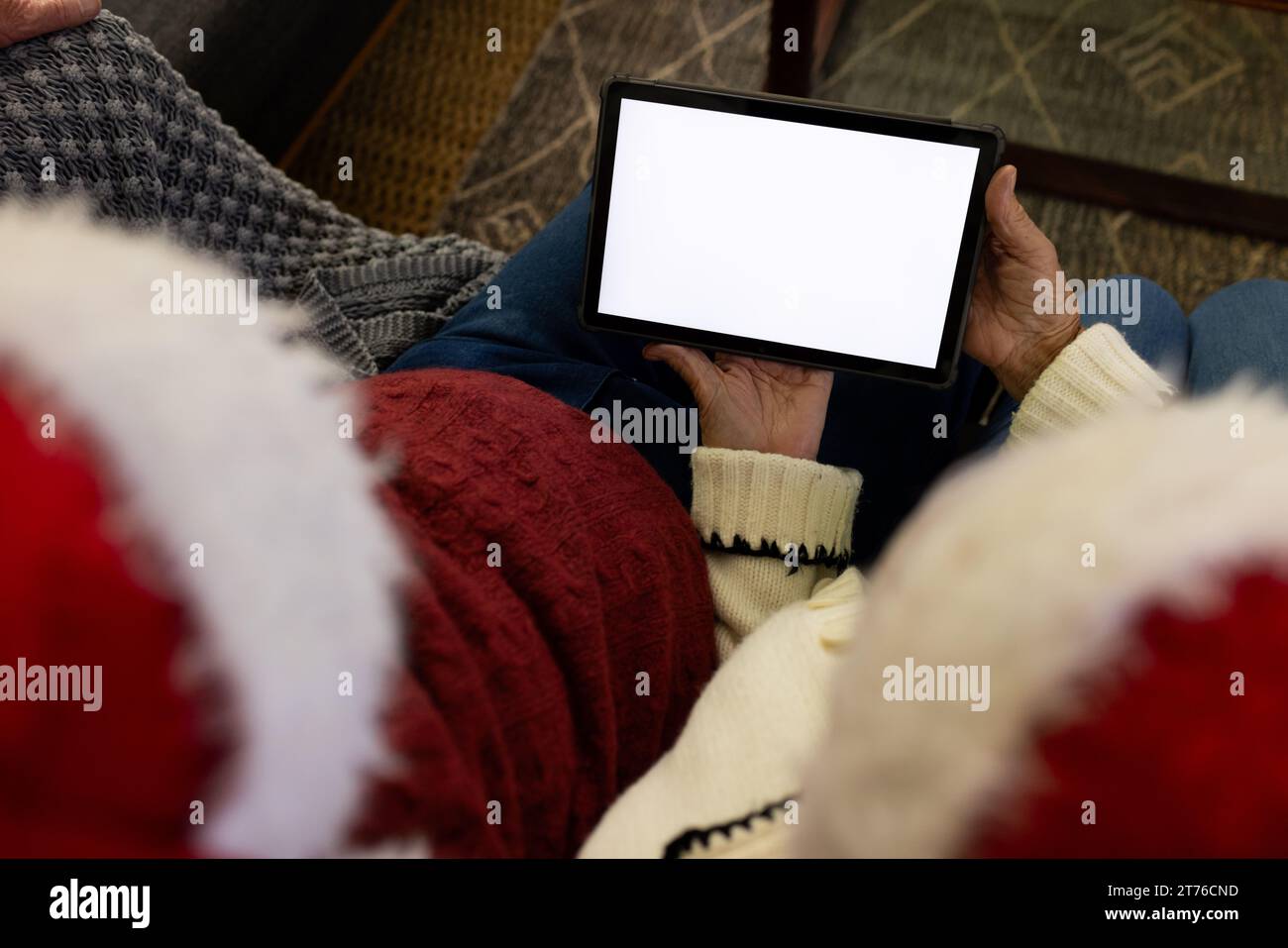 Couple senior caucasien dans les chapeaux de santa ayant l'appel vidéo de tablette de noël, espace de copie sur l'écran Banque D'Images