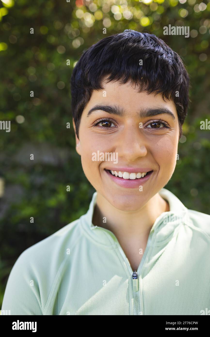 Portrait de femme biracial heureuse avec les cheveux foncés courts souriant dans le jardin ensoleillé Banque D'Images