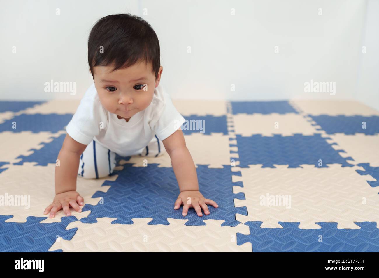 bébé rampant sur un tapis de jeu ou un plancher de scie sauteuse Banque D'Images