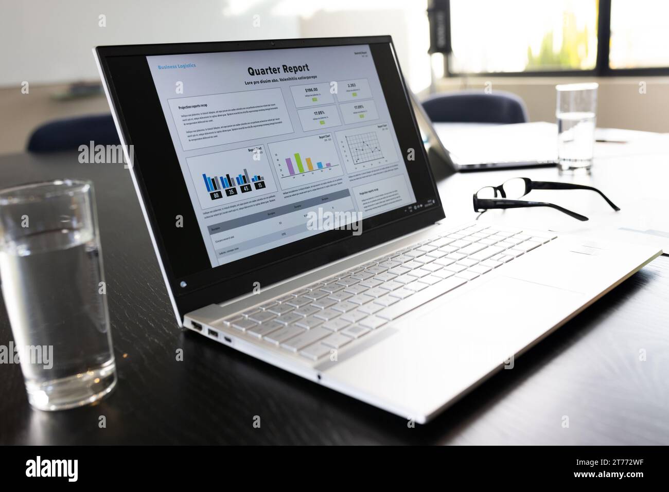 Ordinateur portable avec texte de rapport trimestriel et graphiques sur l'écran sur la table dans la salle de réunion de bureau Banque D'Images