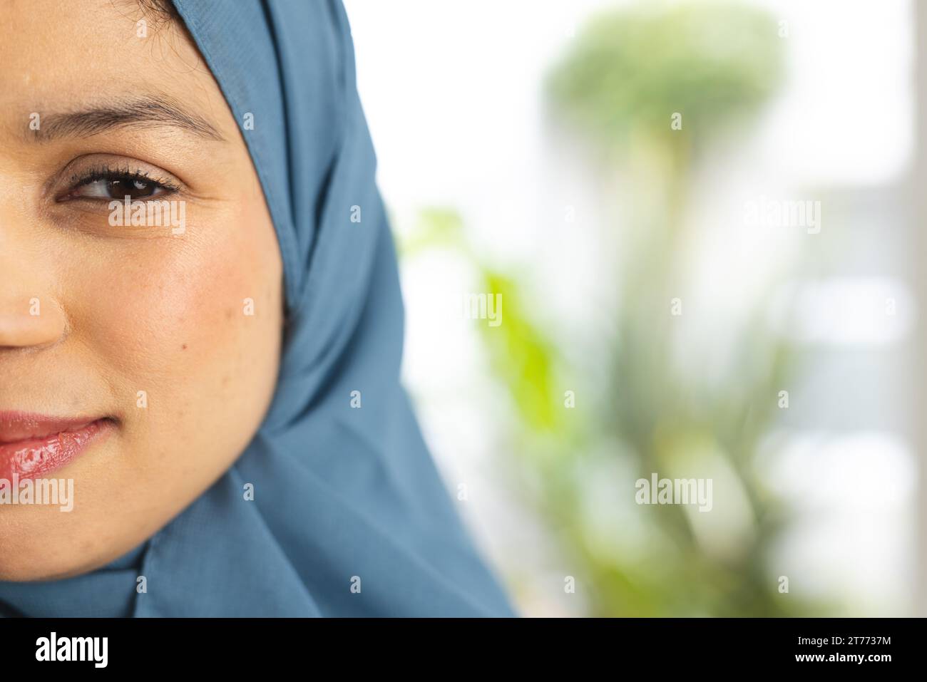 Demi portrait de femme biracial heureuse dans le hijab à la maison ensoleillée avec espace de copie Banque D'Images