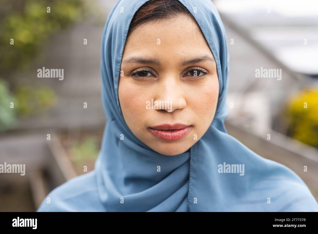 Portrait de femme biraciale en hijab bleu dans une nature ensoleillée Banque D'Images