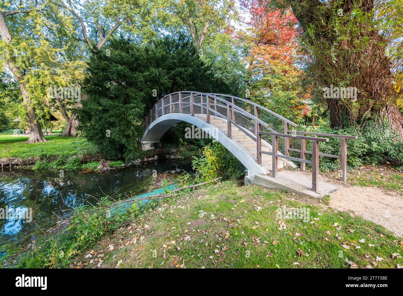 Pont au-dessus de l'étang dans le parc entouré d'arbres verts. Banque D'Images