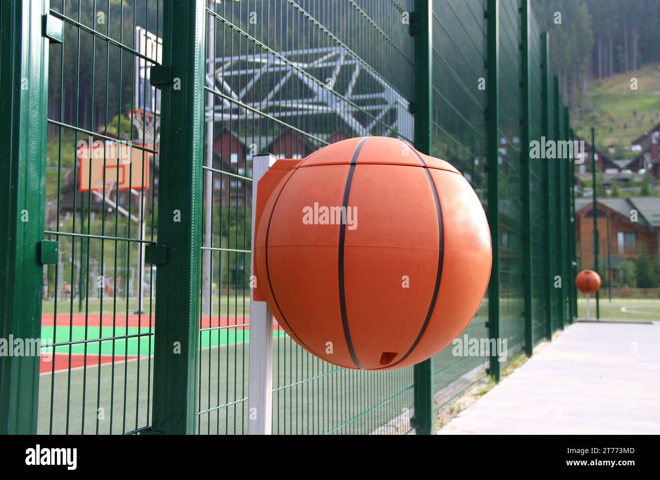 Poubelles en plastique en forme de basket-ball sur le trottoir en béton autour du terrain de basket-ball Banque D'Images