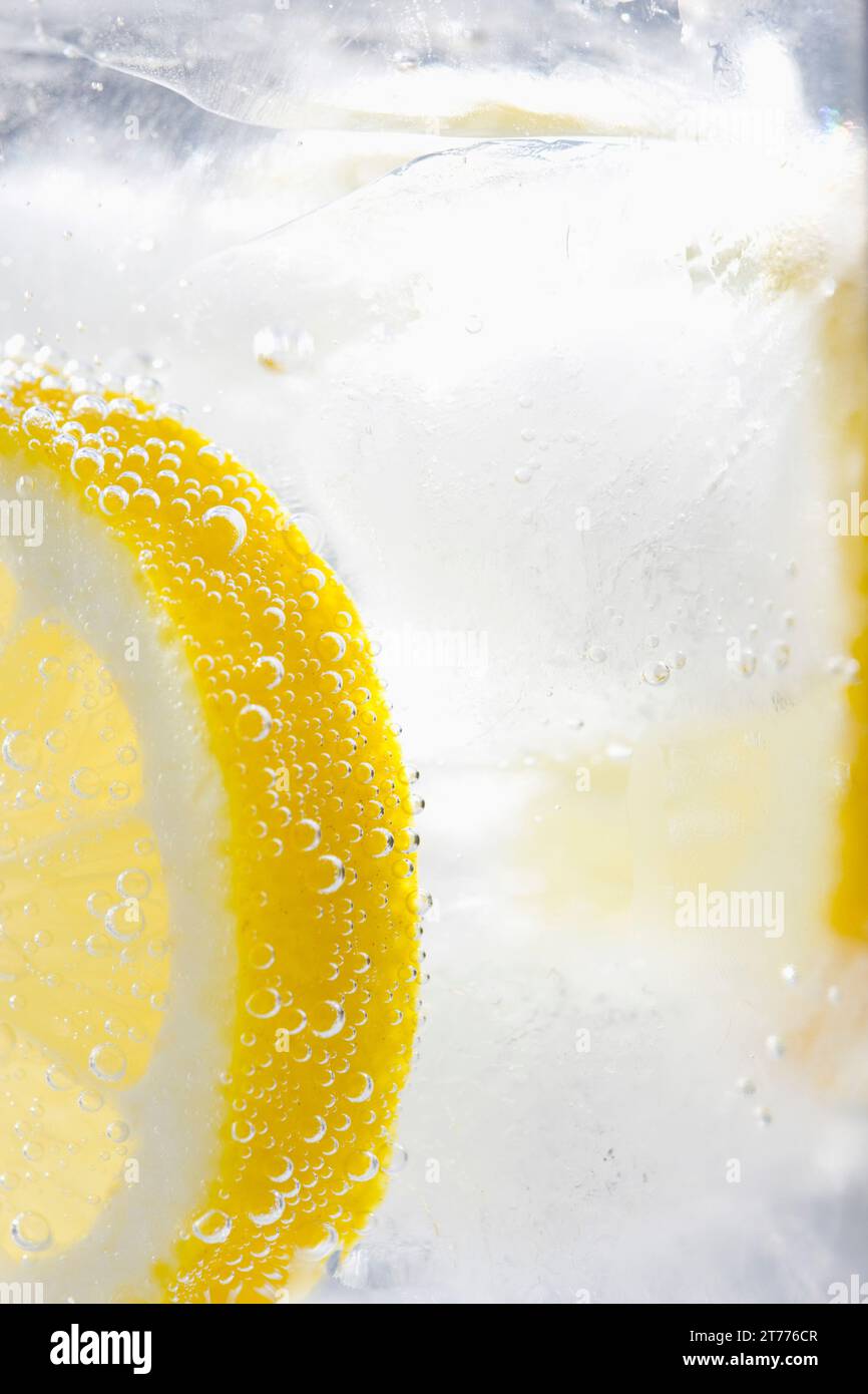 Extreme close up d'une tranche de citron flottant dans l'eau glacée mousseux Banque D'Images