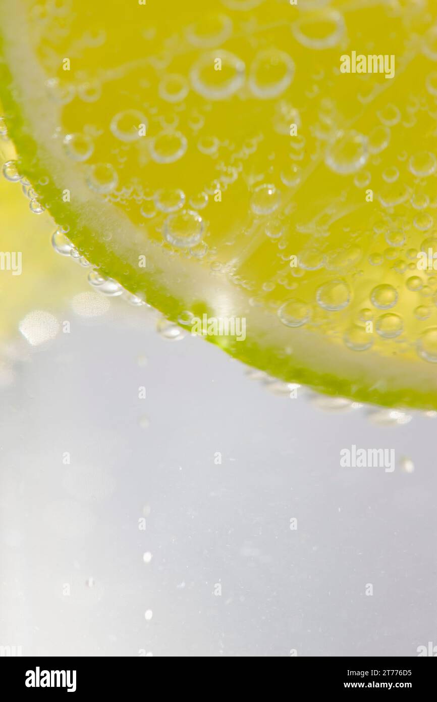 Extreme close up d'une tranche de lime flottant dans l'eau pétillante Banque D'Images