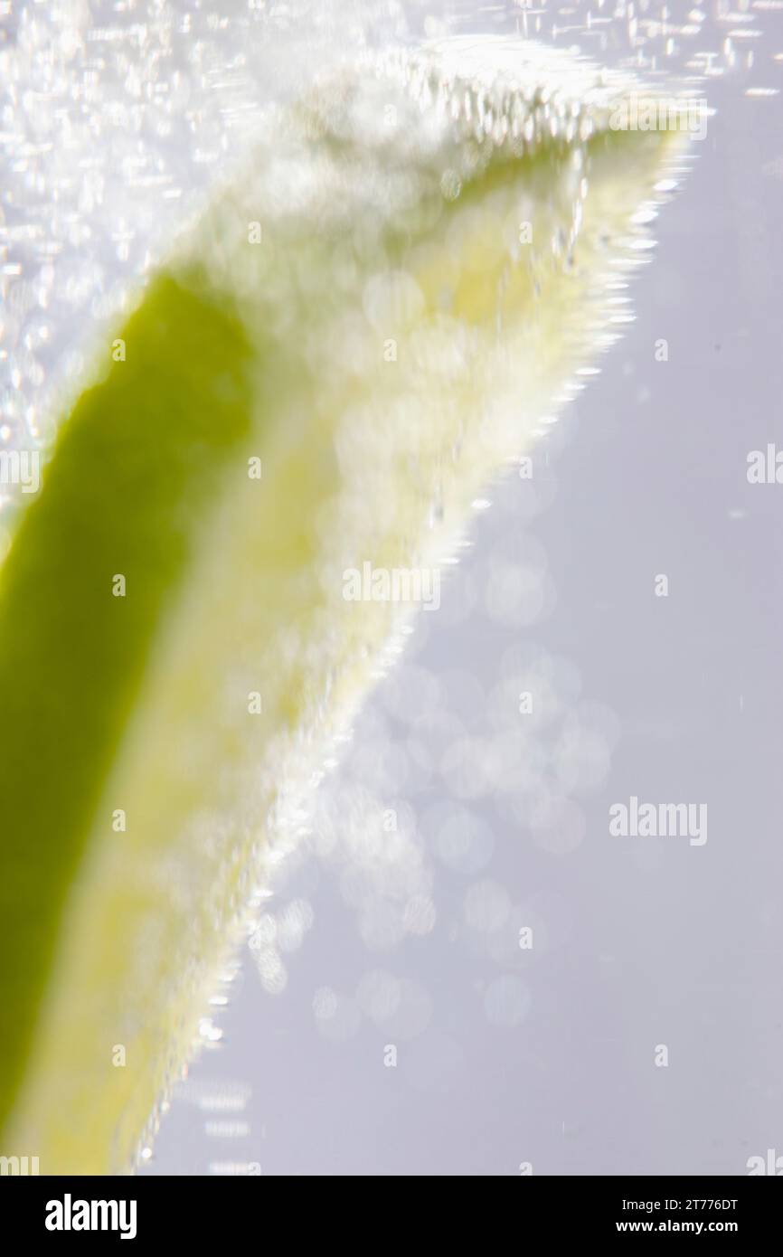 Extreme close up d'une tranche de lime flottant dans l'eau pétillante Banque D'Images