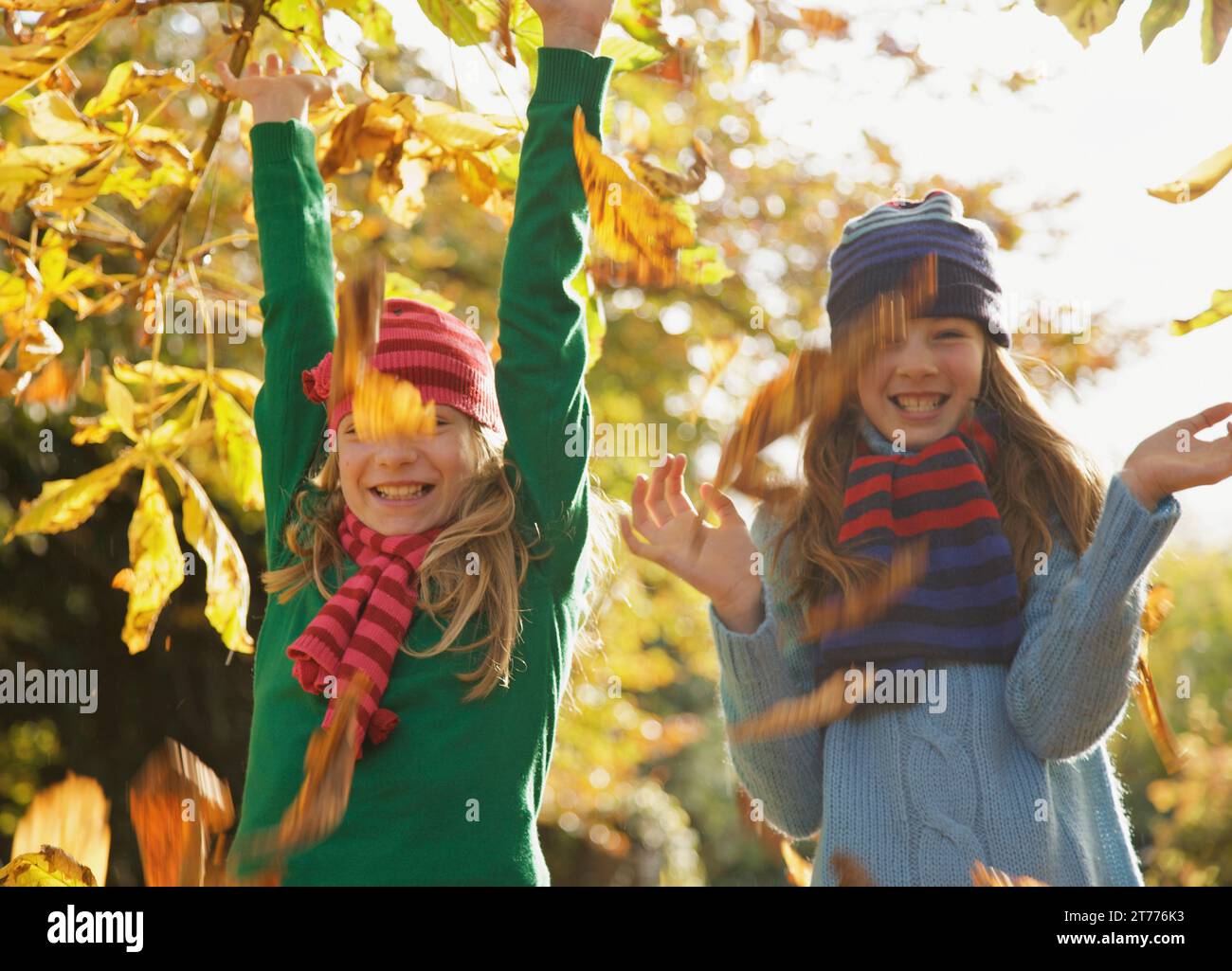 Deux filles souriant laisse jeter en l'air Banque D'Images