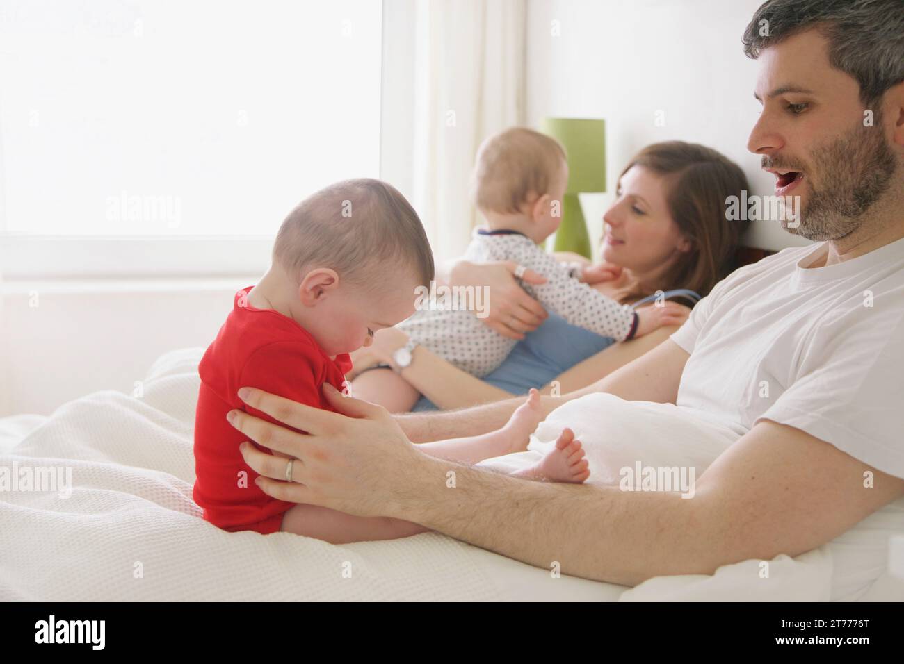 Couple au lit avec bébé jumeaux Banque D'Images