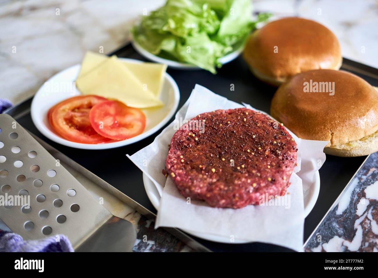 Patty de hamburger nature morte et ingrédients sur plateau Banque D'Images