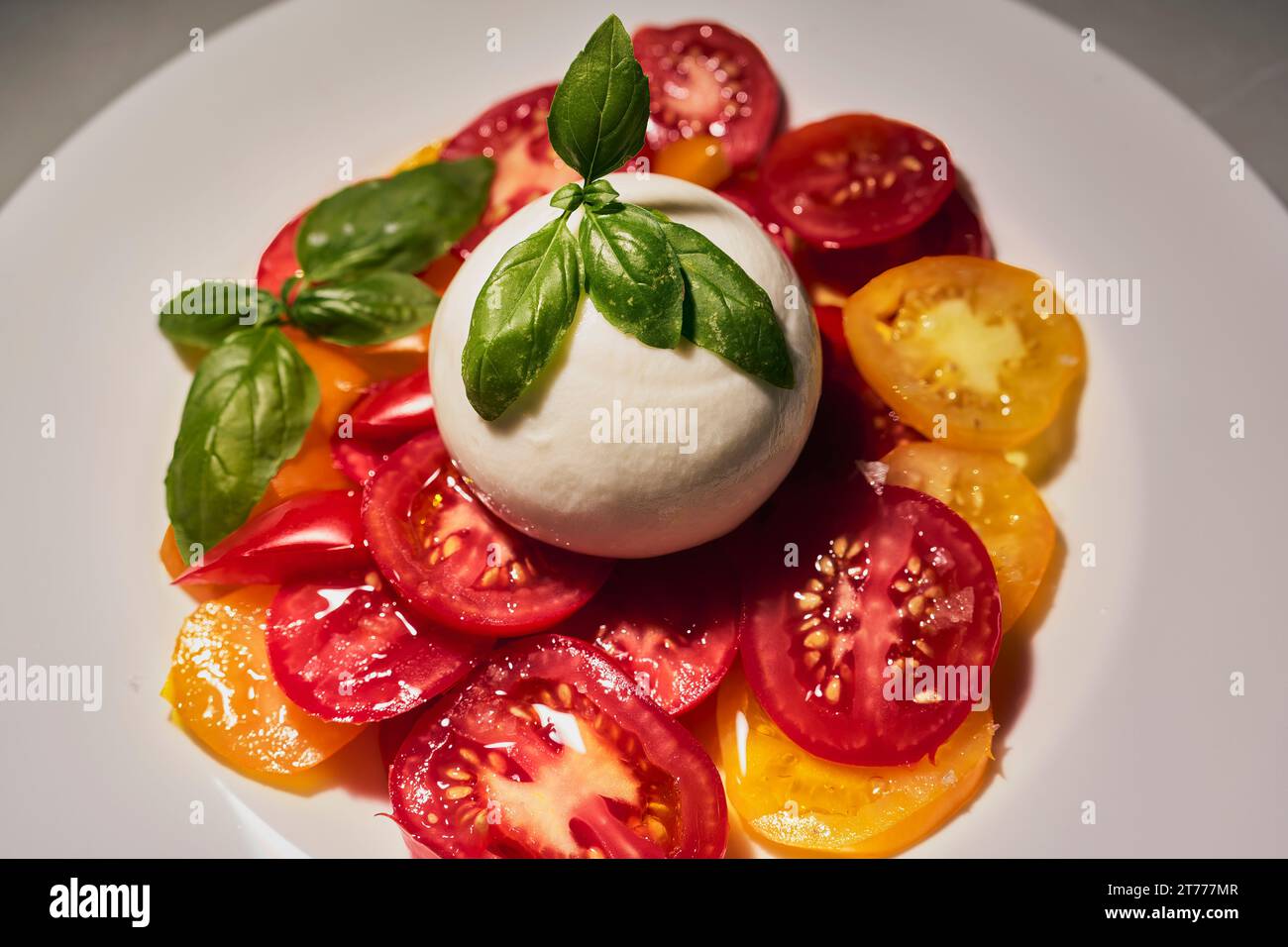 Close up nature morte salade de caprese fraîche avec tomates juteuses, mozzarella fouettée et basilic frais Banque D'Images