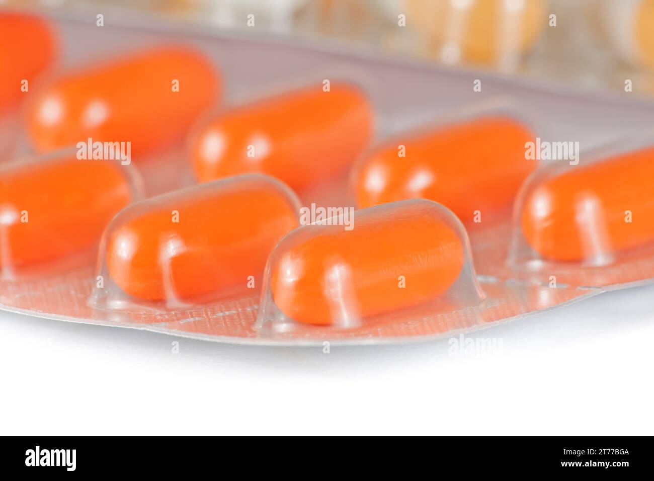 détail des pilules orange emballées dans blister isolé sur la table blanche Banque D'Images