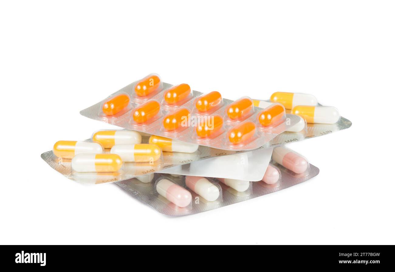 pile de pilules de médecine et capsules emballées dans des blisters isolés sur la table blanche Banque D'Images