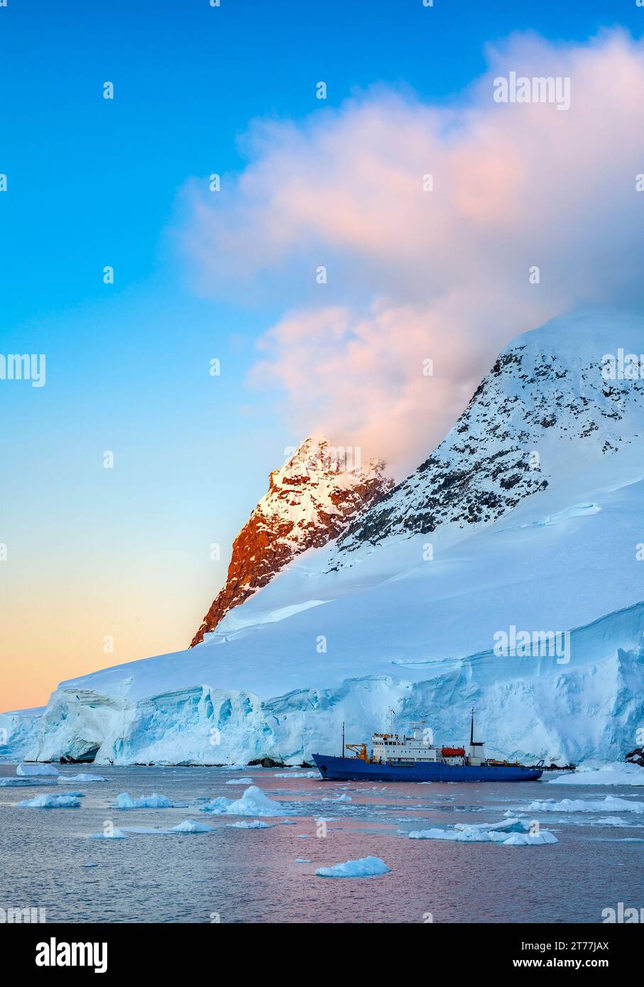 Soleil de minuit et brise-glace touristique dans le canal de Lamaire sur la péninsule antarctique en Antarctique. Banque D'Images