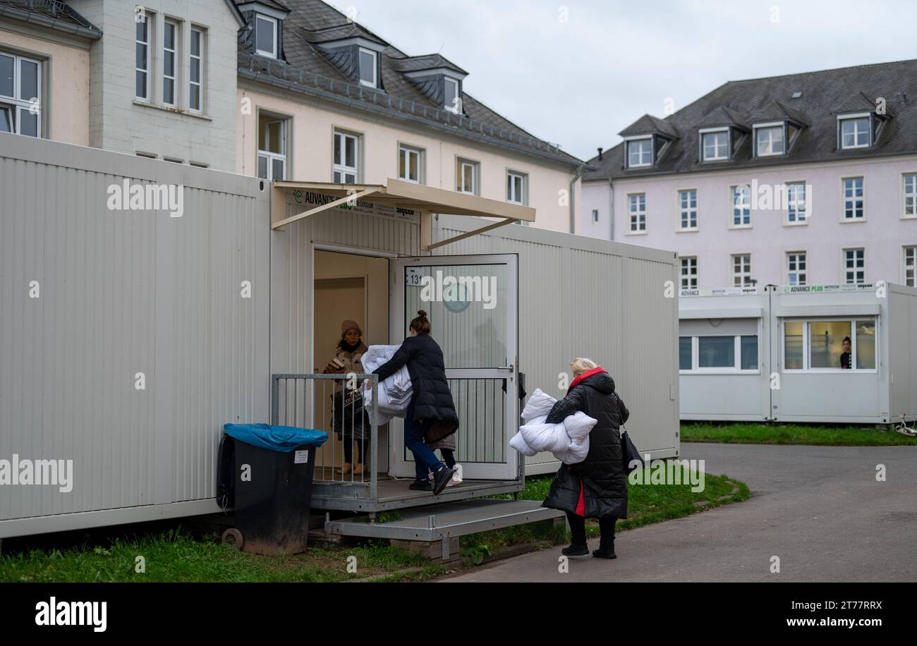 14 novembre 2023, Rhénanie-Palatinat, Trèves : les femmes réfugiées se rendent dans un conteneur au centre d'accueil pour demandeurs d'asile (AFA) à Trèves après avoir reçu leur literie. Photo : Harald Tittel/dpa Banque D'Images