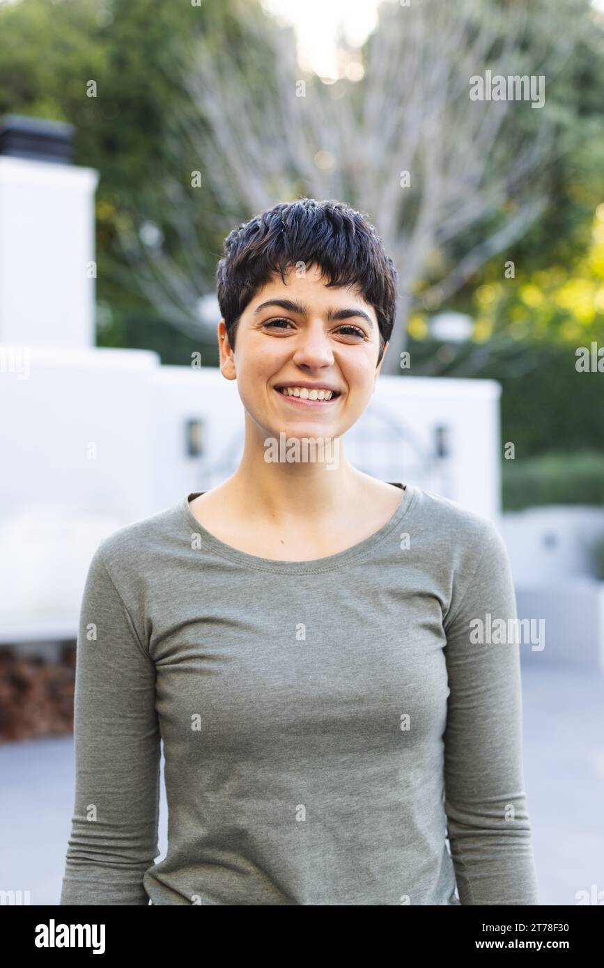 Portrait de femme biracial heureuse avec les cheveux foncés courts debout sur la terrasse de jardin souriant Banque D'Images