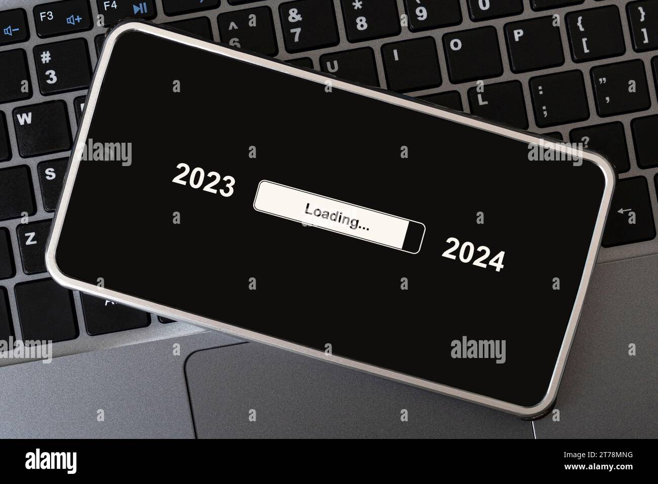 le concept de changer l'année de 2023 à 2024. smartphone sur le clavier de l'ordinateur avec le processus de chargement de la nouvelle année. fin 2023 Banque D'Images