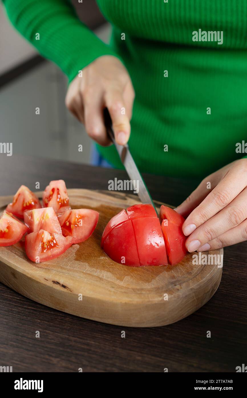 Femme coupe la tomate pour la cuisson de la salade de légumes. Cuisine maison. Banque D'Images