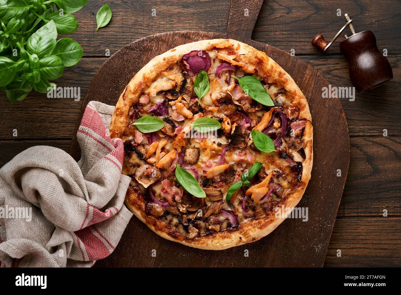 Pizza. Pizza traditionnelle au bacon avec jambon, champignons, concombre mariné et fromage et ingrédients de cuisson tomates basilic sur fond de table en bois. IT Banque D'Images