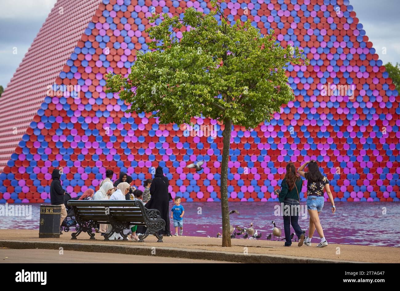 Les gens se détendent à la Serpentine avec la sculpture flottante de Christo et Jeanne-Claude appelé le mastaba de Londres en arrière-plan, Londres, Royaume-Uni. Banque D'Images