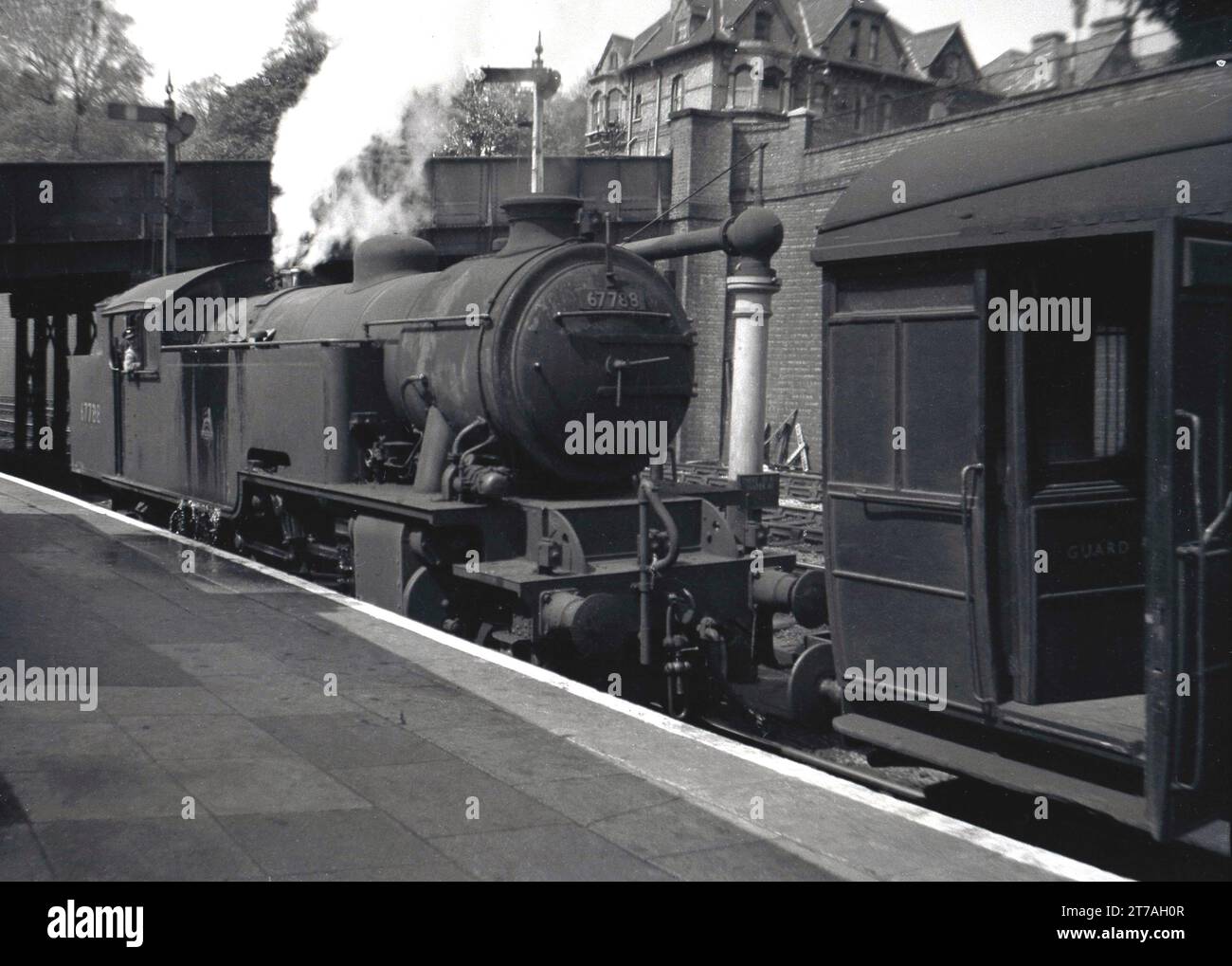 Années 1950, historique, une locomotive à vapeur de l'époque, 67788, sur un quai d'une gare, Angleterre, Royaume-Uni. Le wagon de chemin de fer en face a le mot Garde écrit sur la porte. Construite par Robert Stephenson & Hawthorn, la locomotive LNER L1 Class est entrée en service en 1950 au dépôt de Neasden, à Londres. Elle a été retirée en 1962. Banque D'Images