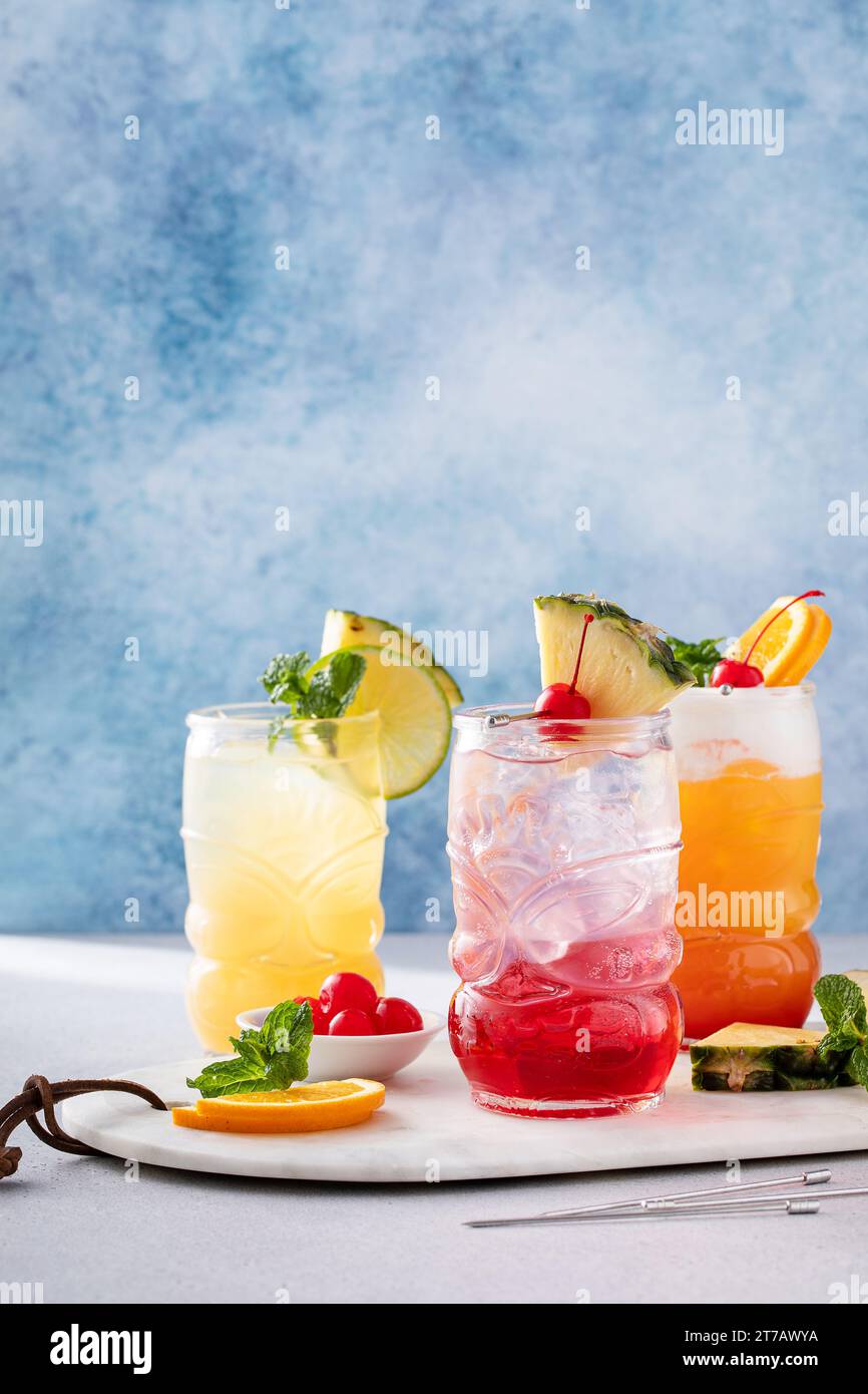Cocktails tiki tropicaux avec mousse froide, garnis de tranches d'orange, cerise et menthe fraîche Banque D'Images
