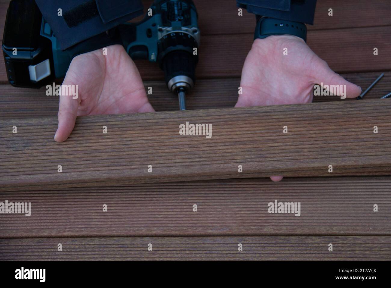 Le menuisier de terrasse tient les panneaux de bois ivrés en gros plan sur la construction de terrasse Banque D'Images