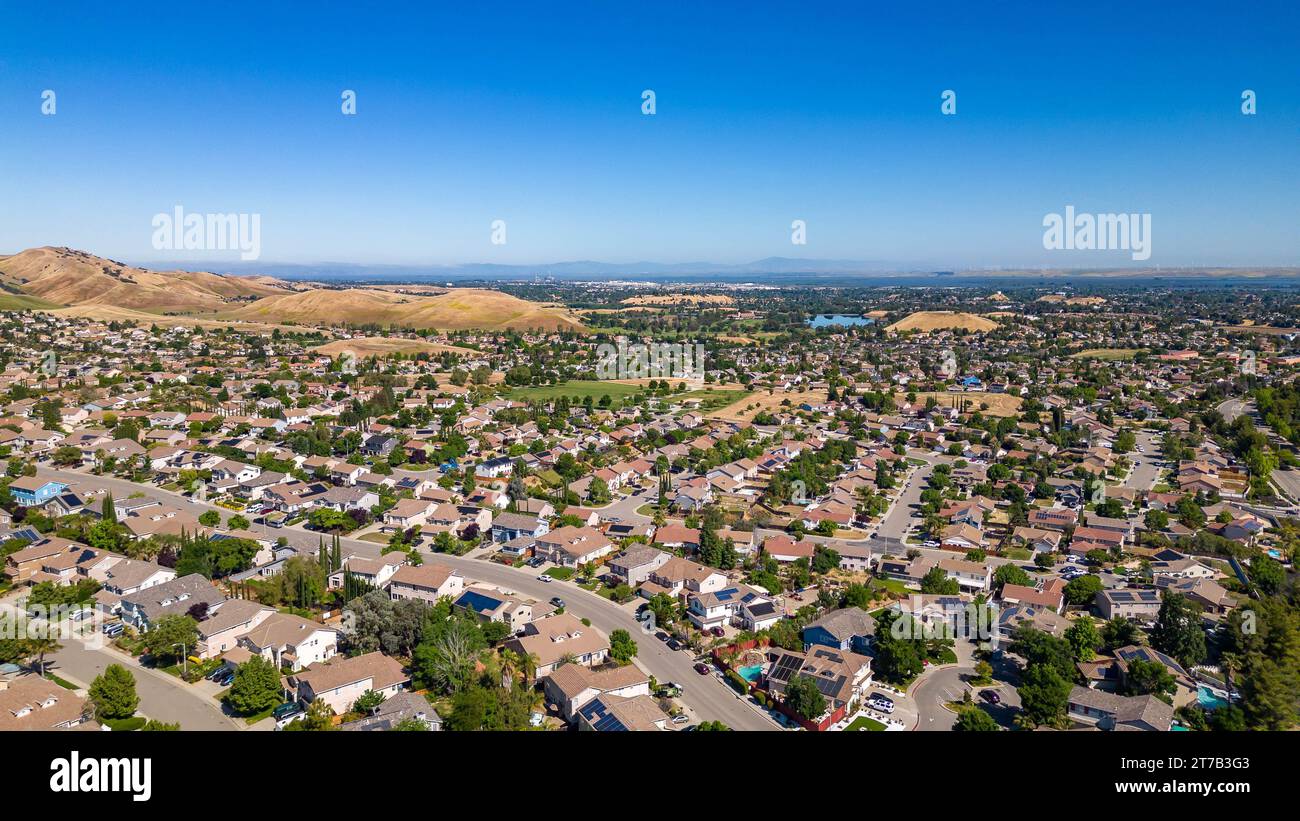 Images aériennes au-dessus d'une communauté à Antioch, Californie avec des maisons avec des collines luxuriantes solaires et vertes après la pluie Banque D'Images