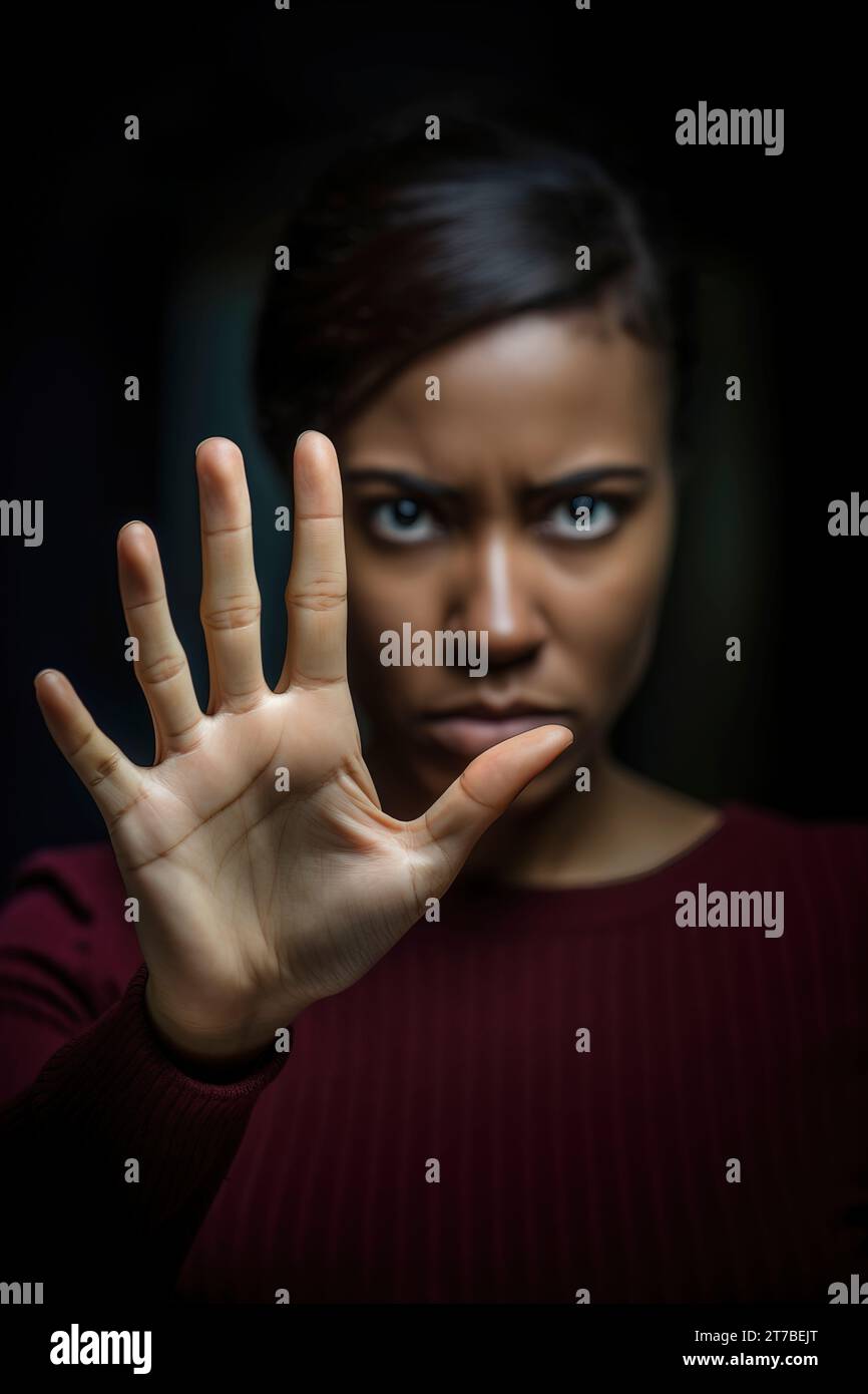 Gros plan intense de la main d'une femme noire dans un geste d'arrêt, son expression sérieuse et dominante. Banque D'Images