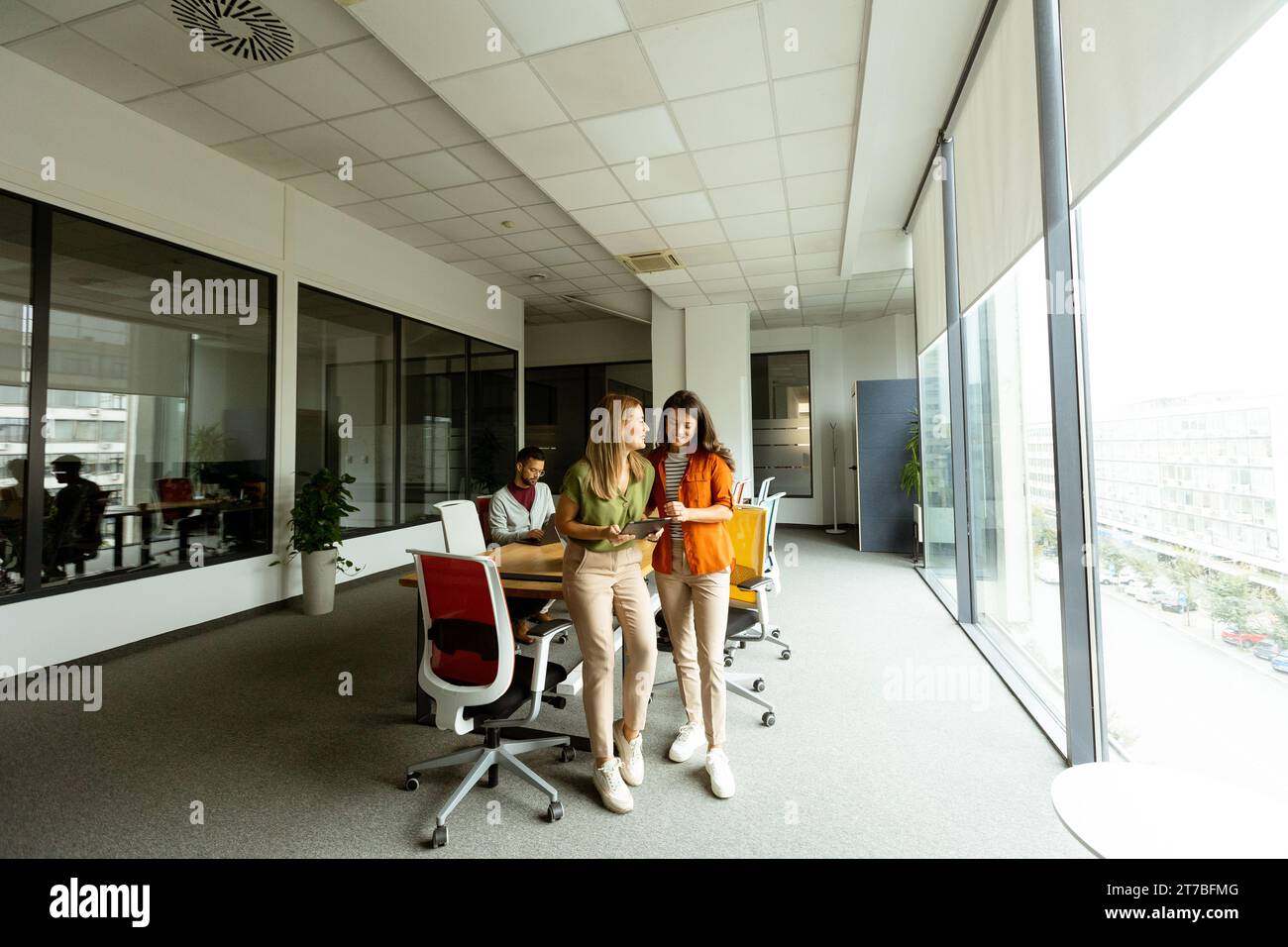 Deux jolies jeunes femmes d'affaires avec tablette numérique dans le bureau moderne Banque D'Images
