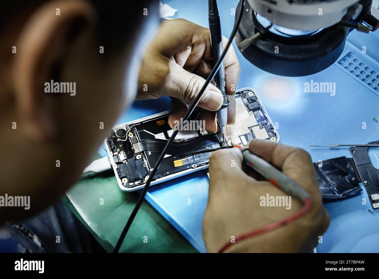 Un technicien réparant un téléphone portable à sa table de travail Banque D'Images