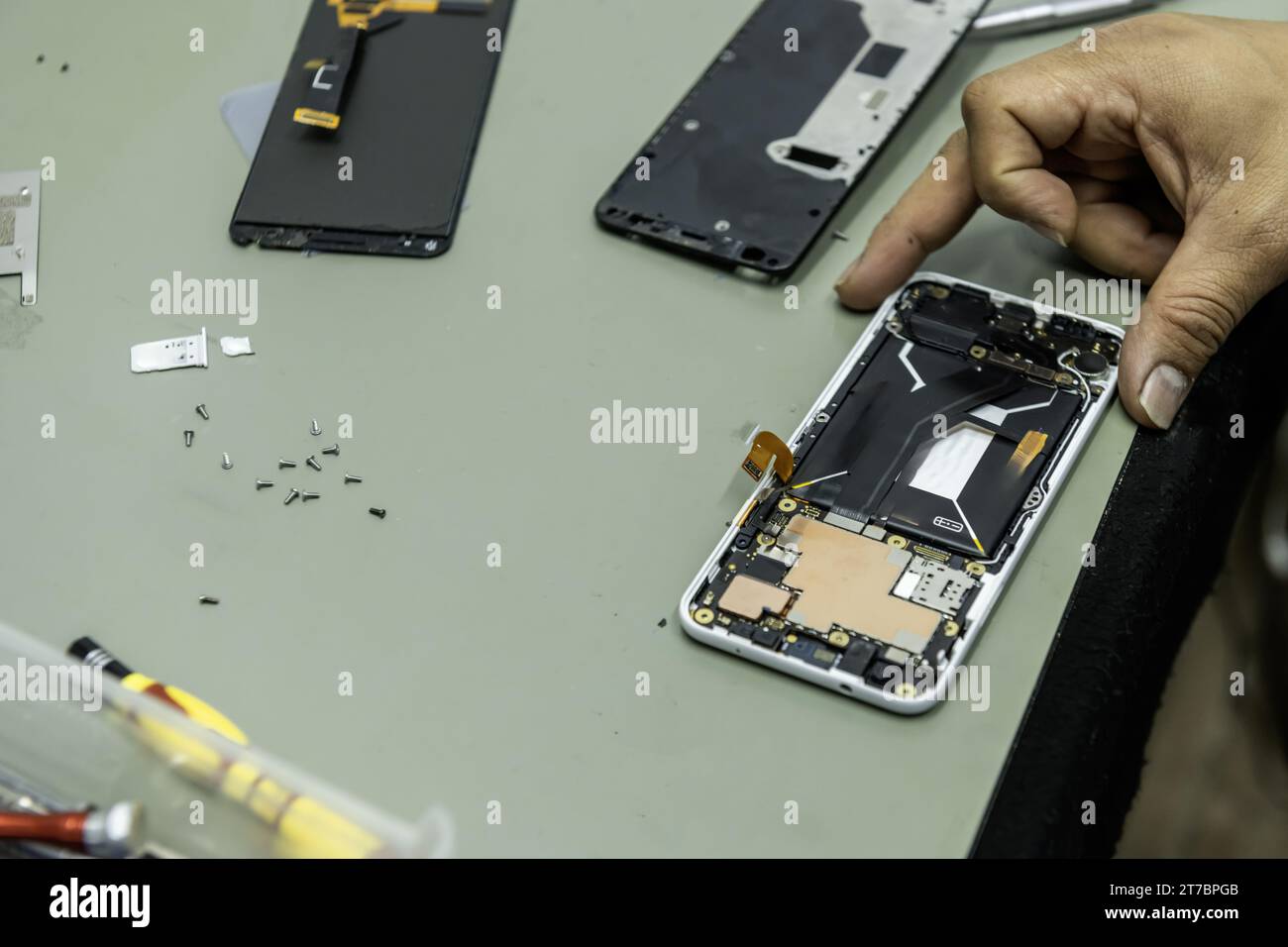 Un technicien a un téléphone ouvert réparateur sur sa table de travail avec une surface contre les interférences électromagnétiques Banque D'Images
