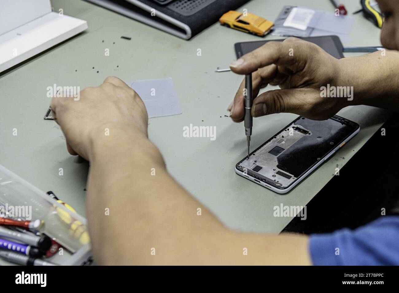 Un technicien démontant l'intérieur d'un téléphone sur la table de son atelier Banque D'Images