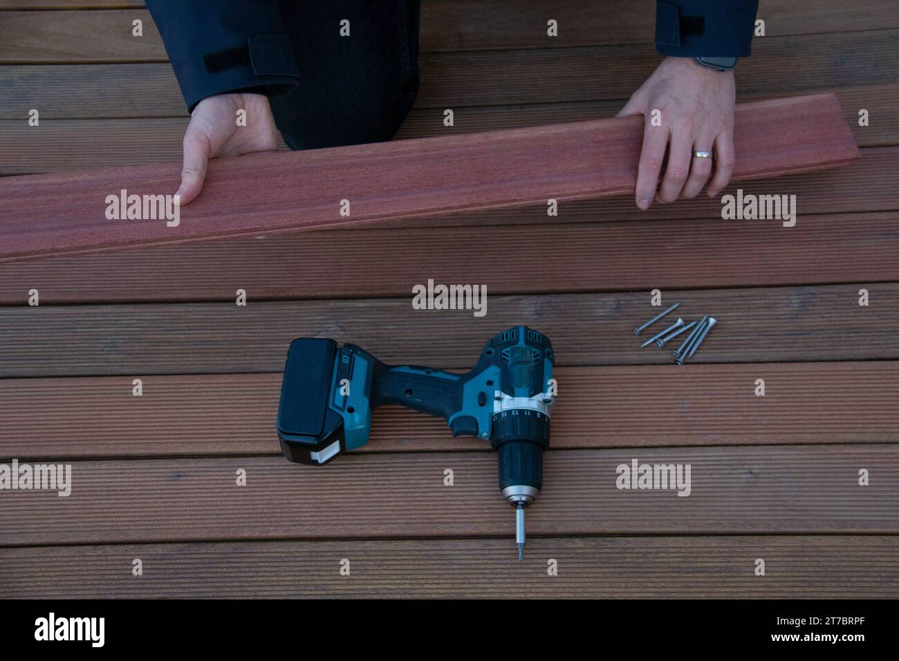 Tournevis électrique sur la construction de terrasse, les mains du charpentier de terrasse tiennent le bois de bois ivre Banque D'Images