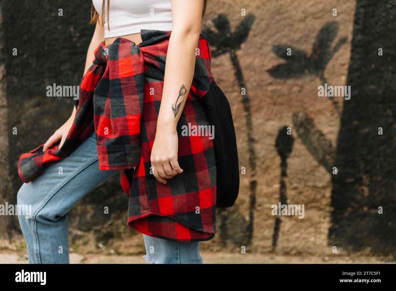 Femme avec fleur tatouer sa main debout mur avant Banque D'Images