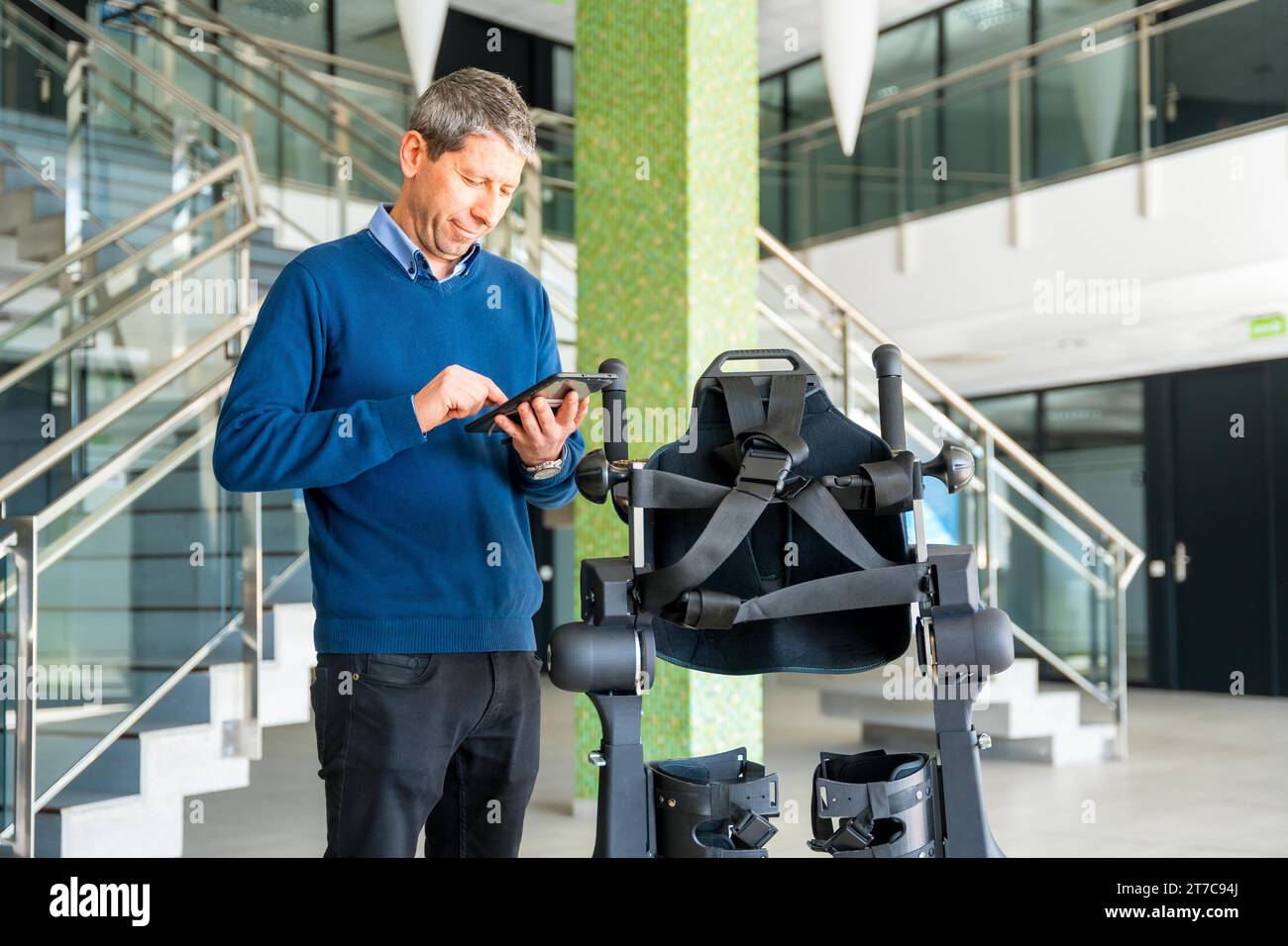 Ingénieur informatique en exosquelette mécanique regardant le robot avec une tablette. Physiothérapie dans un hôpital moderne : squelette robotique. Physiothérapie Banque D'Images