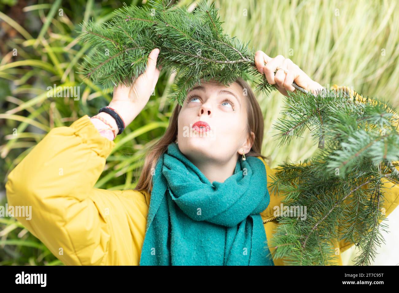 Jeune femme avec une branche verte sur la tête sur un mur végétal comme protection de l'environnement Banque D'Images