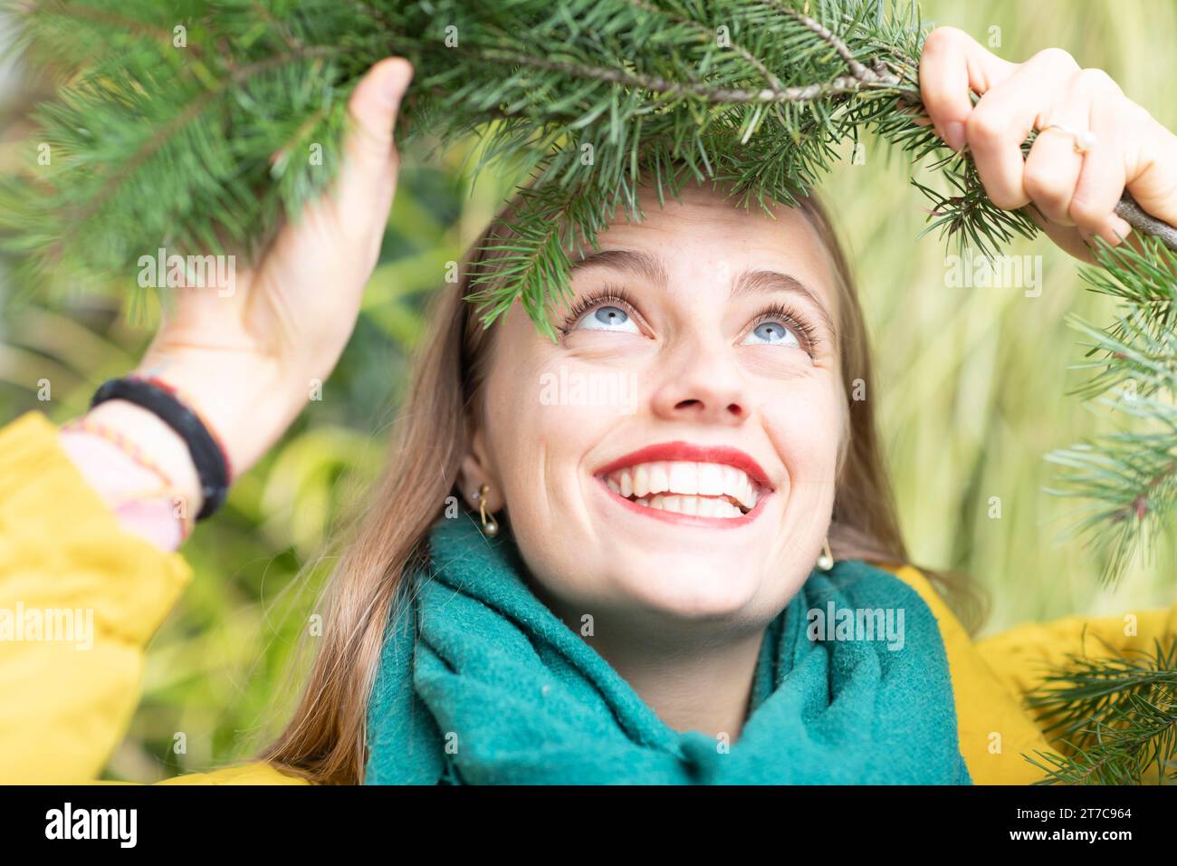 Jeune femme avec une branche verte sur la tête sur un mur végétal Banque D'Images