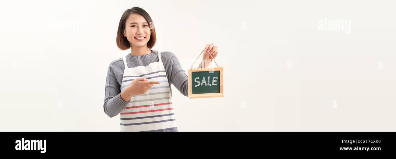 Jeune femme propriétaire de magasin, portant tablier tenant la bannière de mot de VENTE Banque D'Images