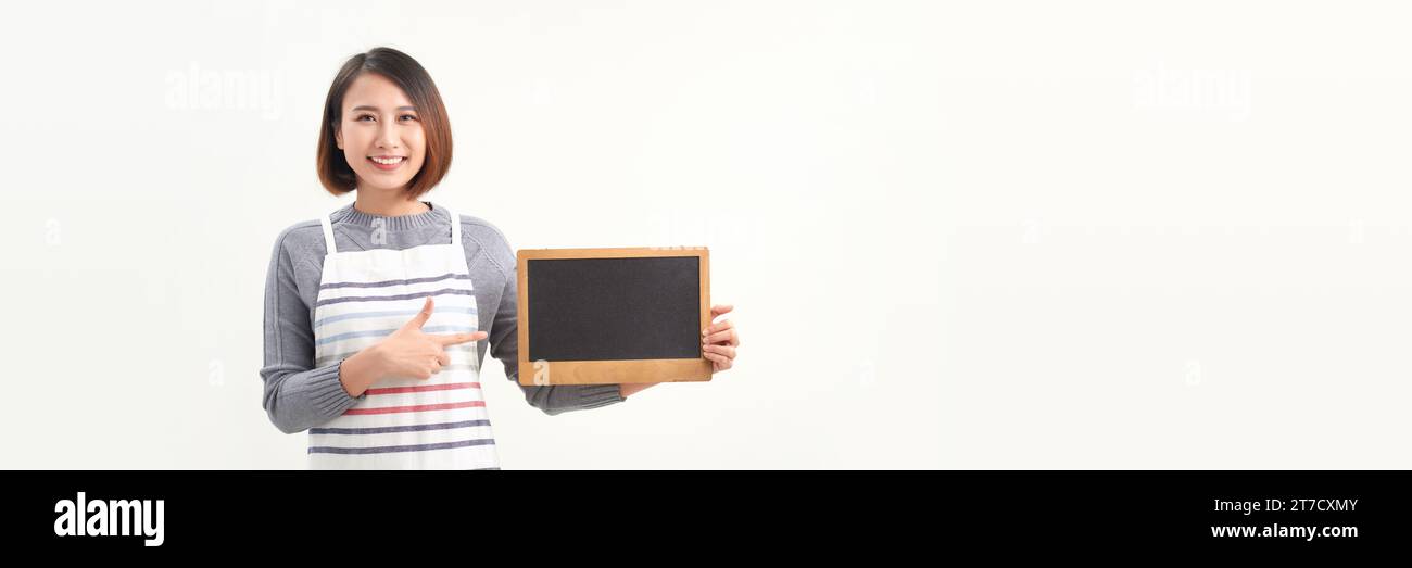 Serveuse se tenant au tableau vide et regardant la caméra tout en se tenant debout sur fond de bannière blanche. Banque D'Images