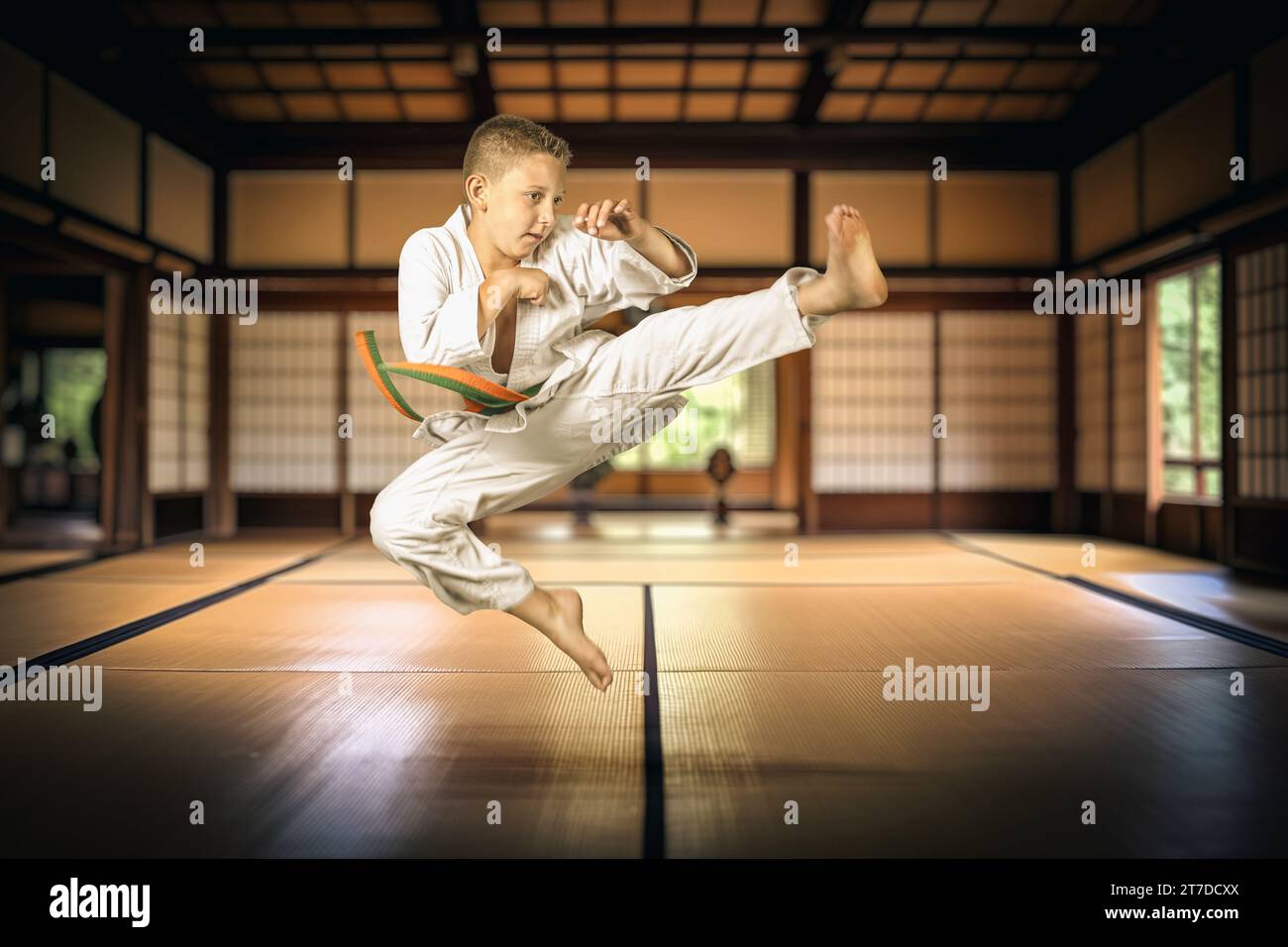 garçon saut pratiquant les arts martiaux dans un dojo traditionnel Banque D'Images