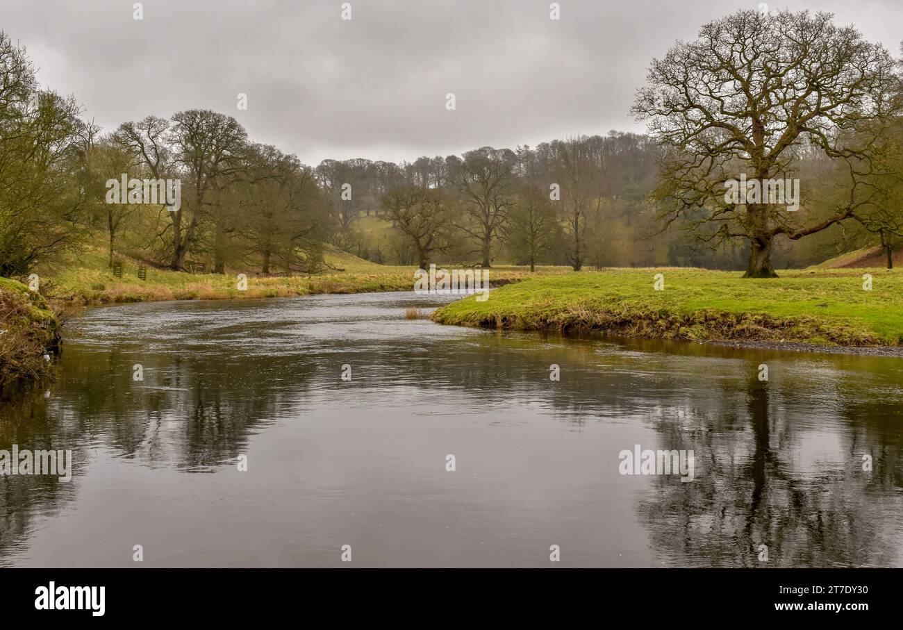 La rivière Kent par un jour couvert d'hiver avec les arbres sur ses rives se reflétant dans l'eau. Banque D'Images