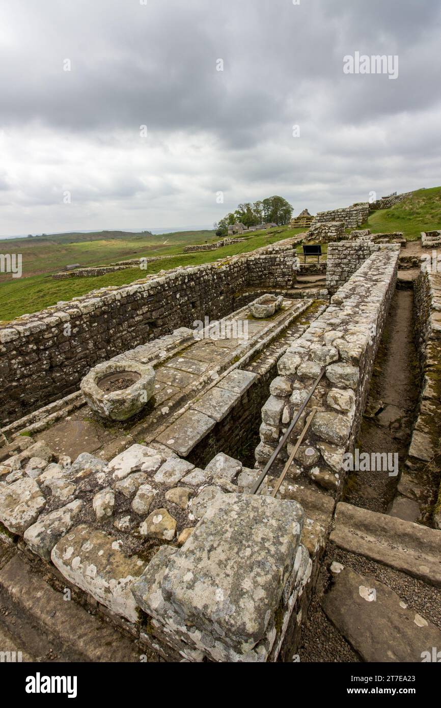 Les ruines des latrines publiques romaines à Housesteads fort le long du mur d’Hadrien dans le nord du Royaume-Uni, avec des nuages de tempête qui se rassemblent en arrière-plan Banque D'Images
